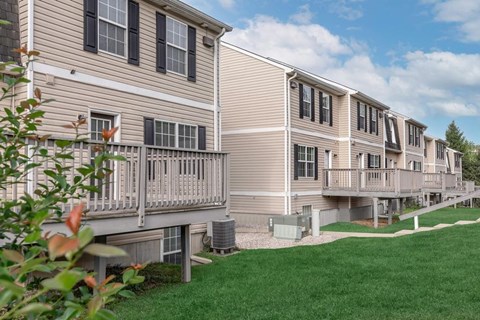 A row of apartment buildings with balconies and green lawns.