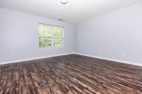 A room with wooden flooring and a window.