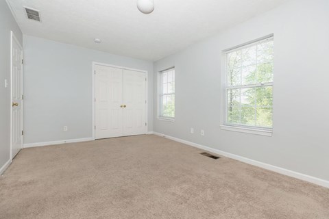 A room with a carpeted floor and a window letting in natural light.