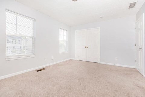 A spacious room with a carpeted floor and white walls.