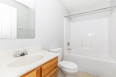 A white bathroom with a toilet, sink, and bathtub.