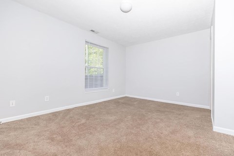 A room with a window and carpeted floor.