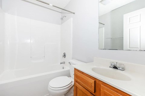 A white toilet sits next to a white bathtub in a bathroom.