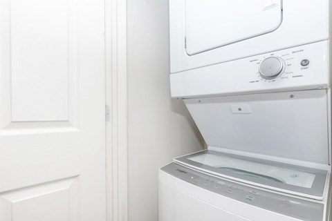 A white dryer is on the wall next to a white door.