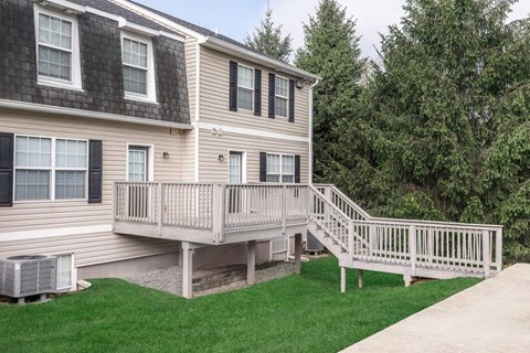 A house with a deck and a tree in the background.