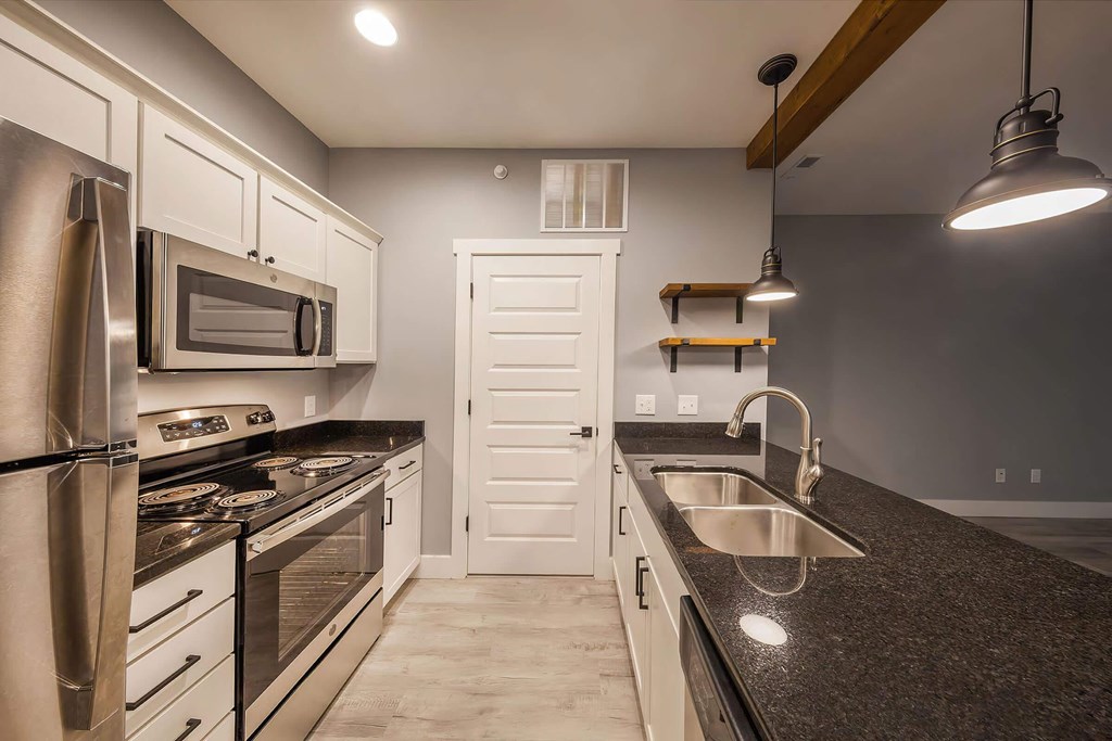 A kitchen with a black countertop and stainless steel appliances.