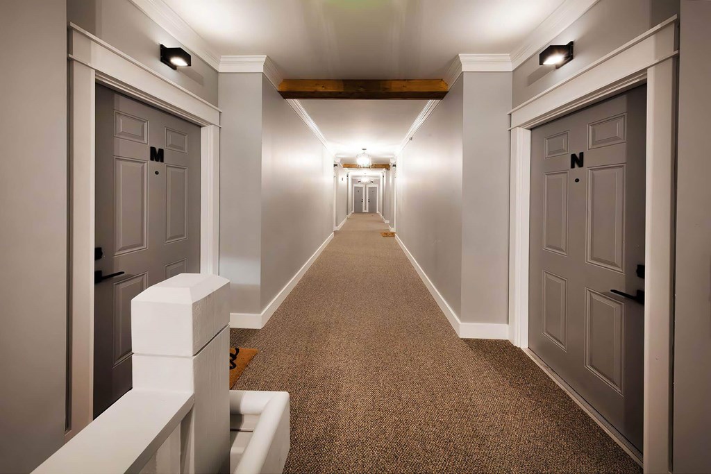 A long hallway with doors on both sides and lights on the ceiling.