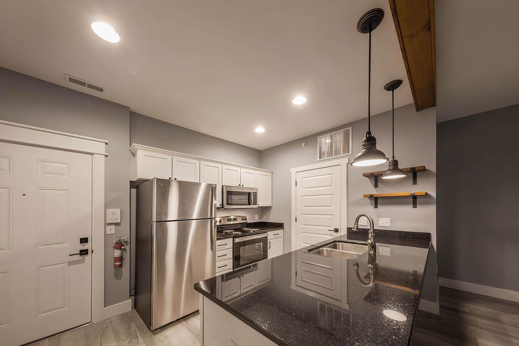 A modern kitchen with a black granite countertop and stainless steel appliances.