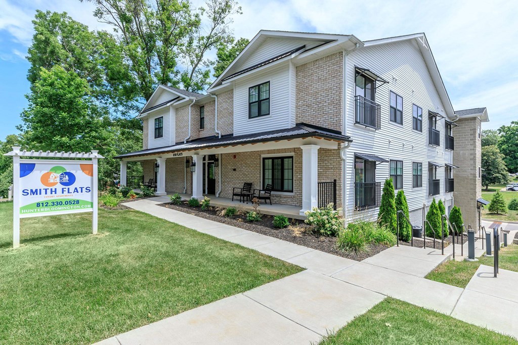 A two-story house with a sign that says "Smith Flats" in front of it.