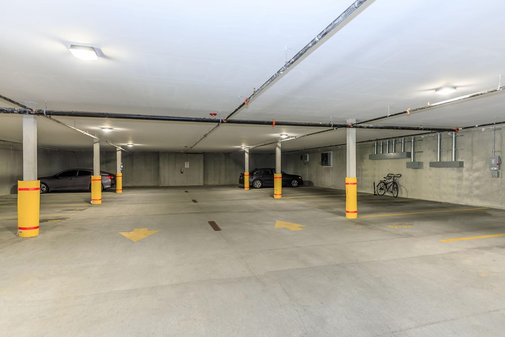 A parking garage with yellow bollards and concrete floors.