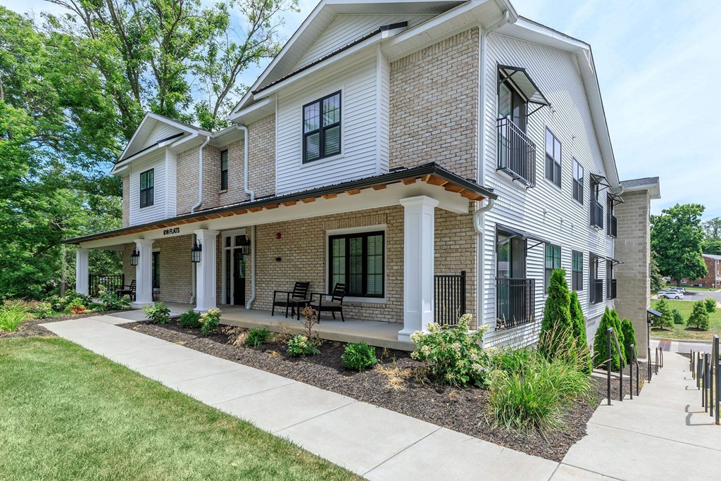 A house with a white and brown exterior and a black railing.