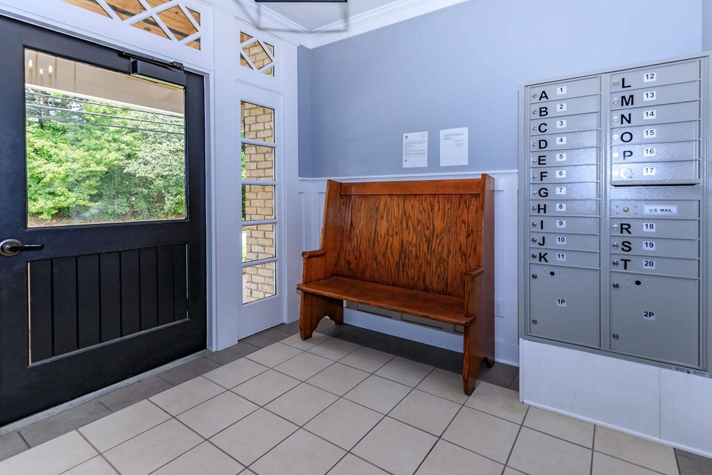 A wooden bench is placed in front of a mailbox.