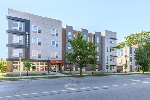A modern apartment building with a blue and white sign on the left side.