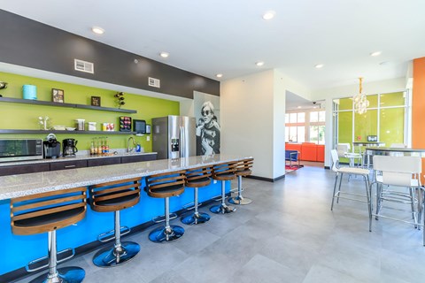 A modern bar with blue stools and a green wall.