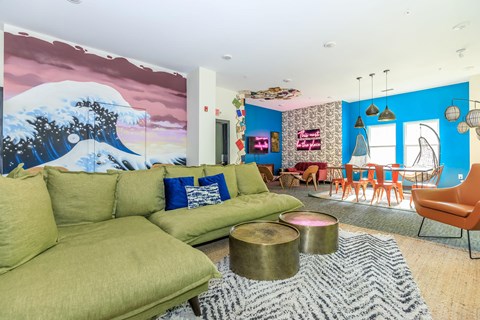 A living room with a large green sofa and a painting of a mountain scene on the wall.