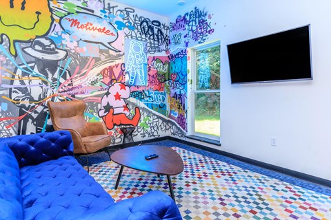 A room with a blue couch and a wall covered in graffiti.