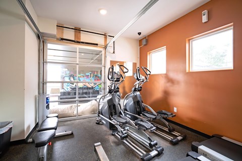A gym with orange walls and a row of treadmills.