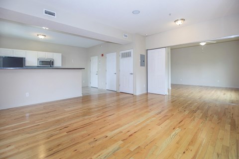 A spacious room with wooden flooring and white walls.
