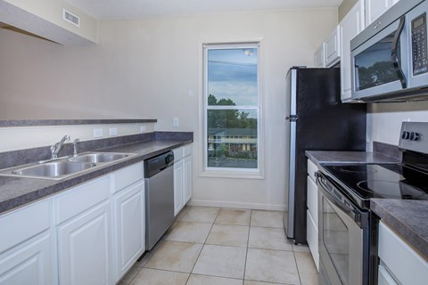 A kitchen with white cabinets and black appliances.