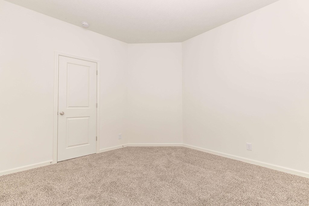 A room with a carpeted floor and a white door.