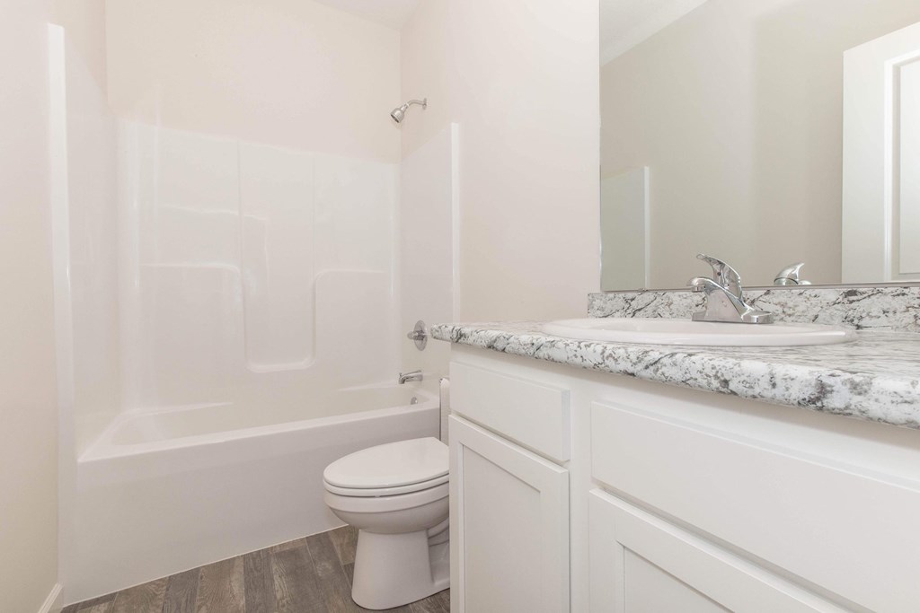 A white toilet sits in a bathroom next to a marble counter.