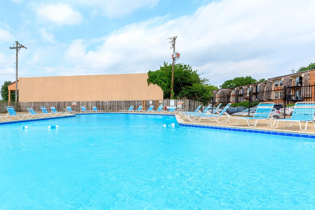 A large swimming pool with blue water and lounge chairs.