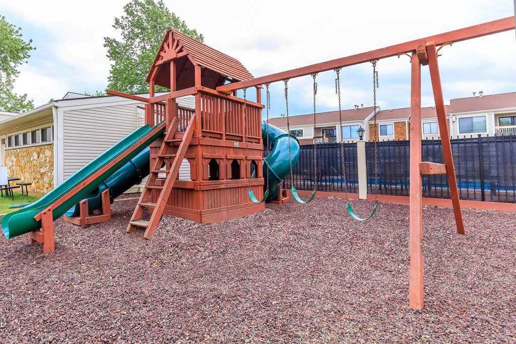 A playground with a green slide and a red wooden structure.