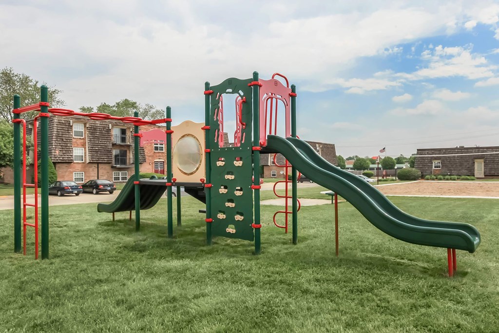 A playground with a green slide and red and green play structure.