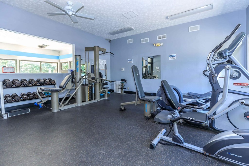 A gym with a variety of equipment including treadmills, weights, and exercise machines.