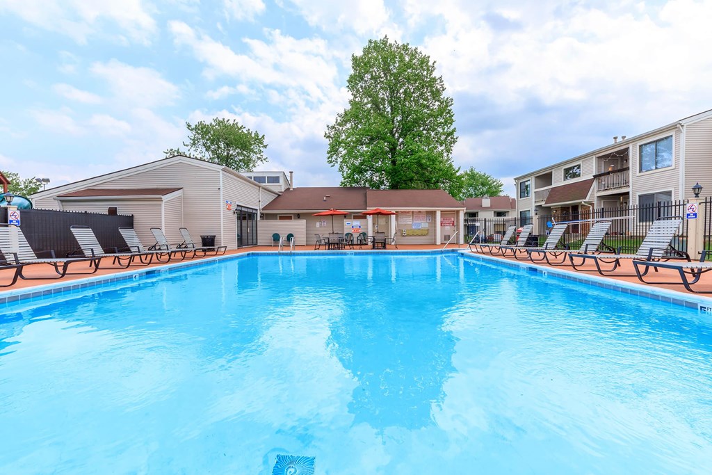 A swimming pool in a residential area with a blue sky and clouds.