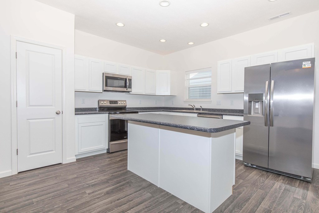 A kitchen with white cabinets and a stainless steel refrigerator.