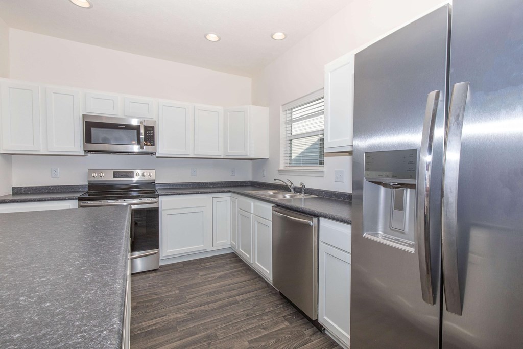 A kitchen with a stainless steel refrigerator and white cabinets.