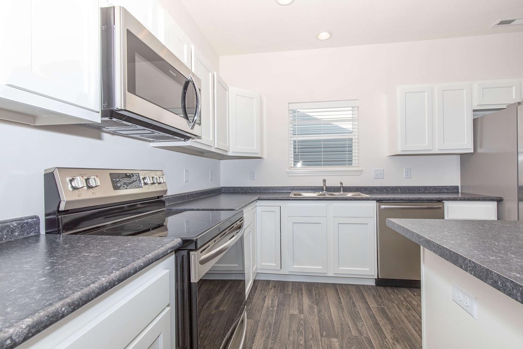 A modern kitchen with white cabinets and a black countertop.
