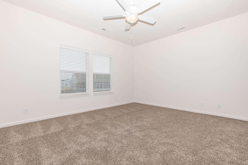 A room with a ceiling fan and carpeted floor.