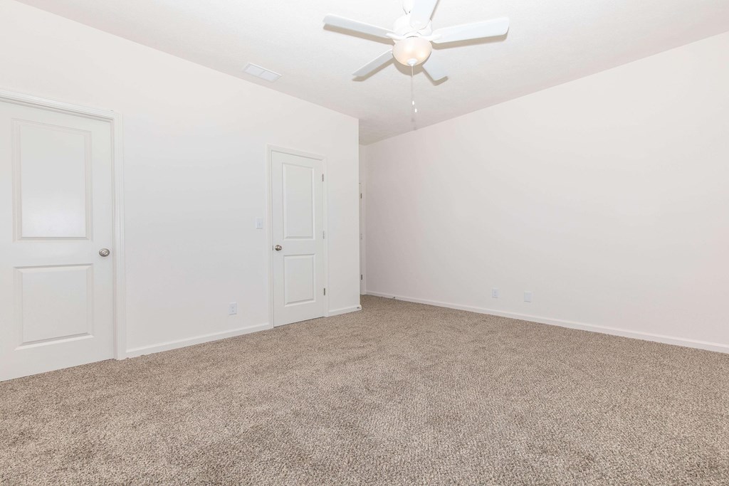 A room with a ceiling fan and carpeted floor.