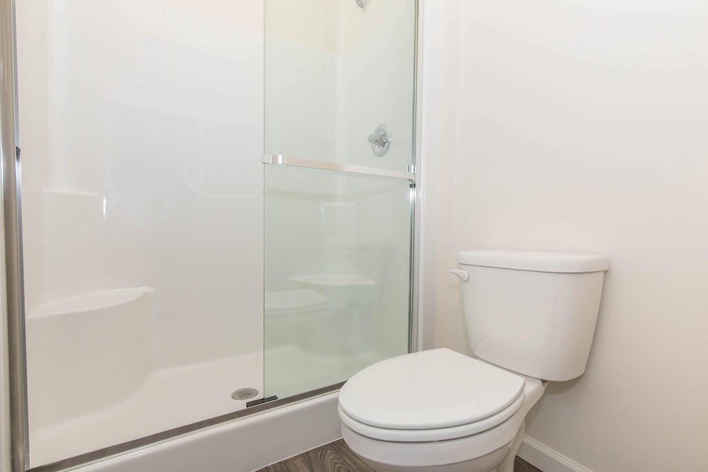 A white toilet sits next to a glass shower stall.