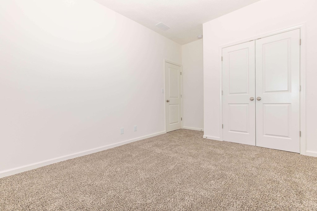 A room with carpeted floor and two doors.