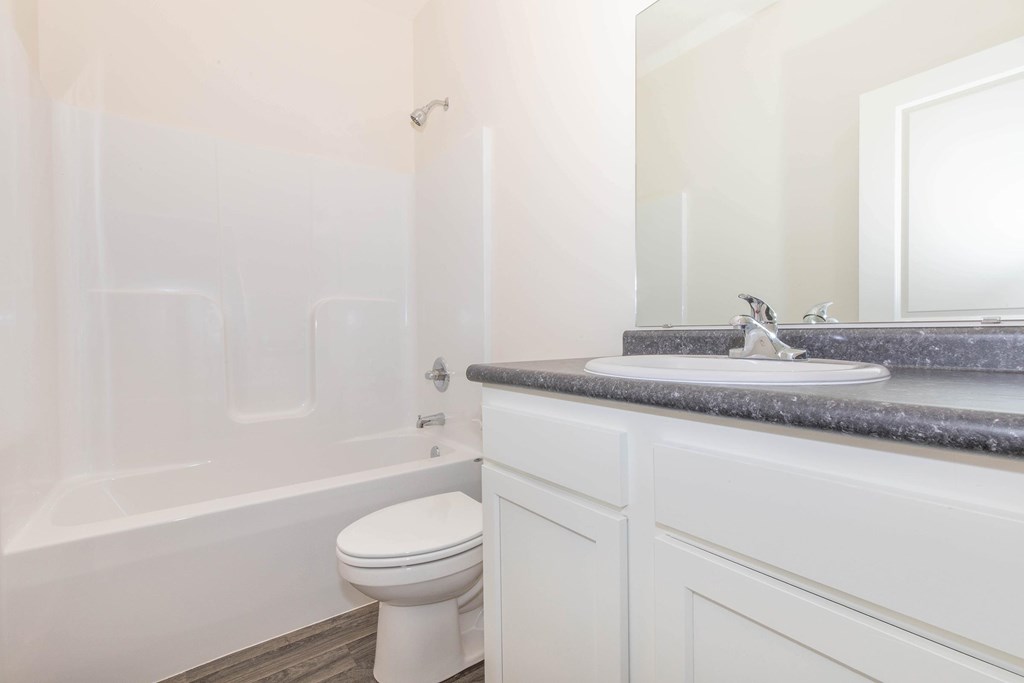 A white toilet sits next to a bathtub in a bathroom.