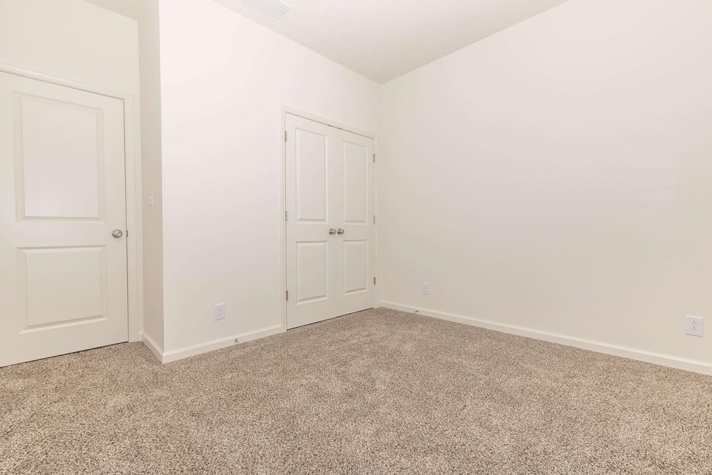 A room with two doors and carpeted floor.