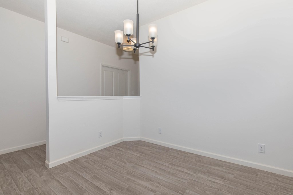 A room with a light fixture and wood flooring.