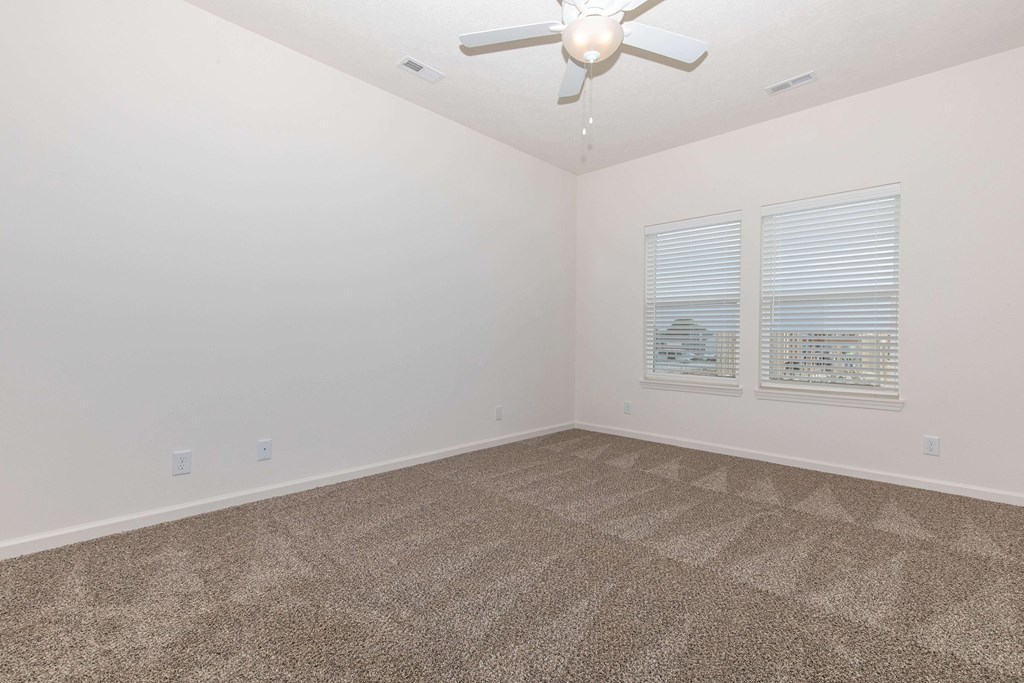 A room with a ceiling fan and carpeted floor.