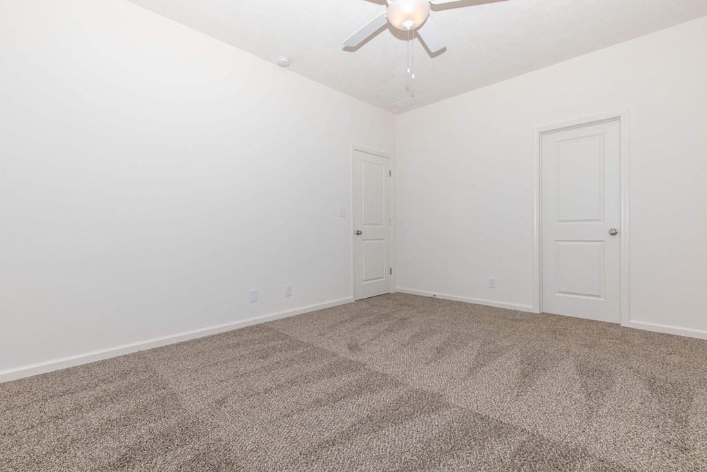 A room with a ceiling fan and carpeted floor.