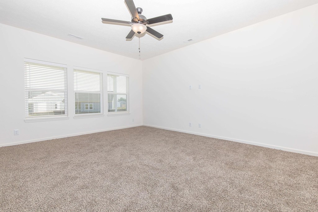 A room with a ceiling fan and carpeted floor.