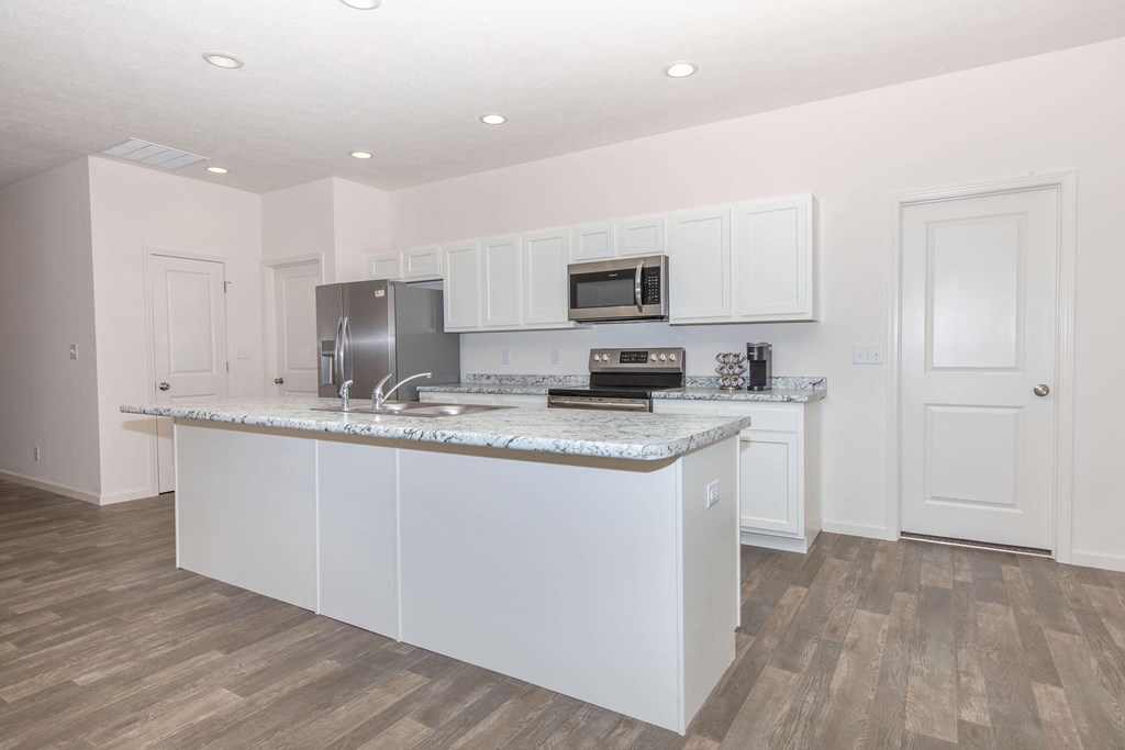 A kitchen with white cabinets and a marble countertop.