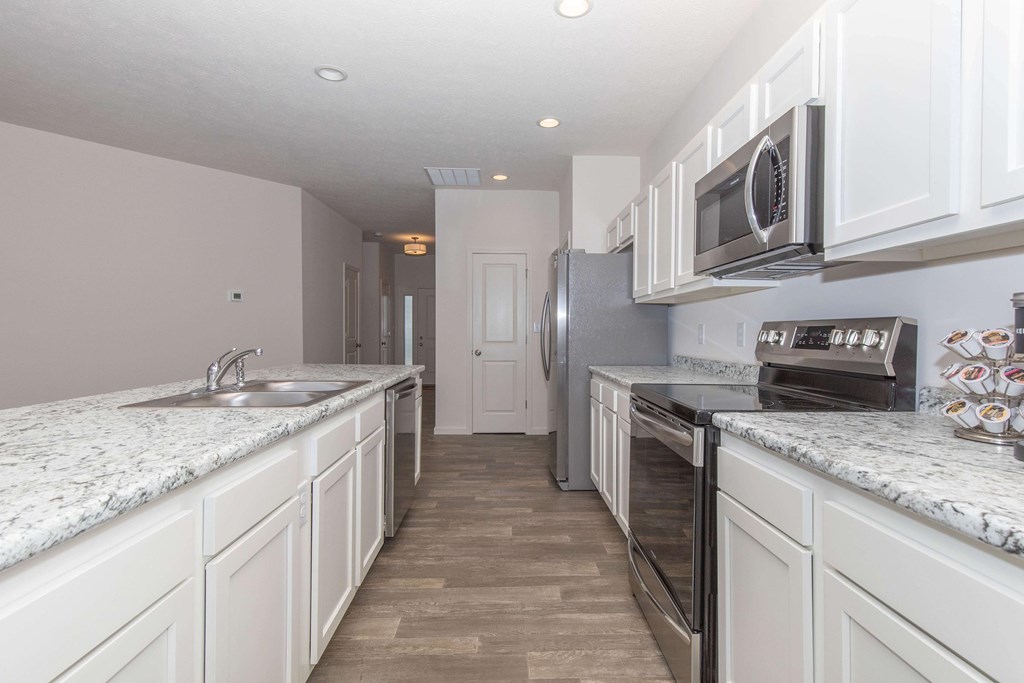 A kitchen with white cabinets and a marble countertop.