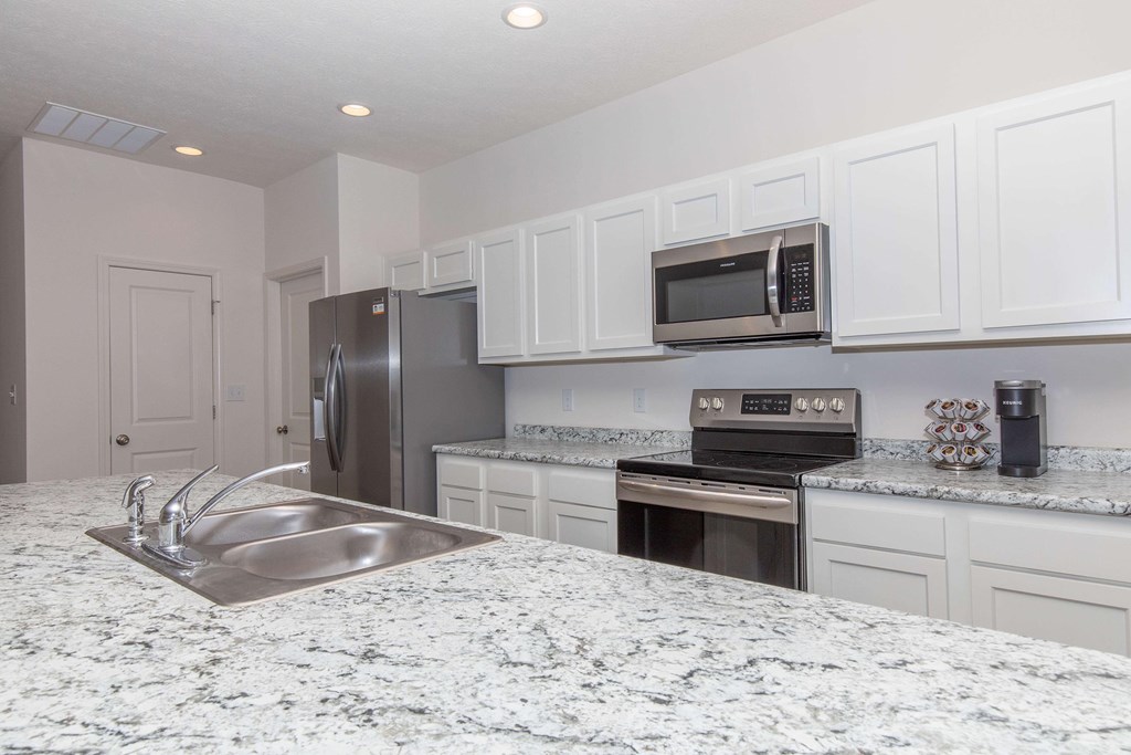 A kitchen with granite countertops and white cabinets.