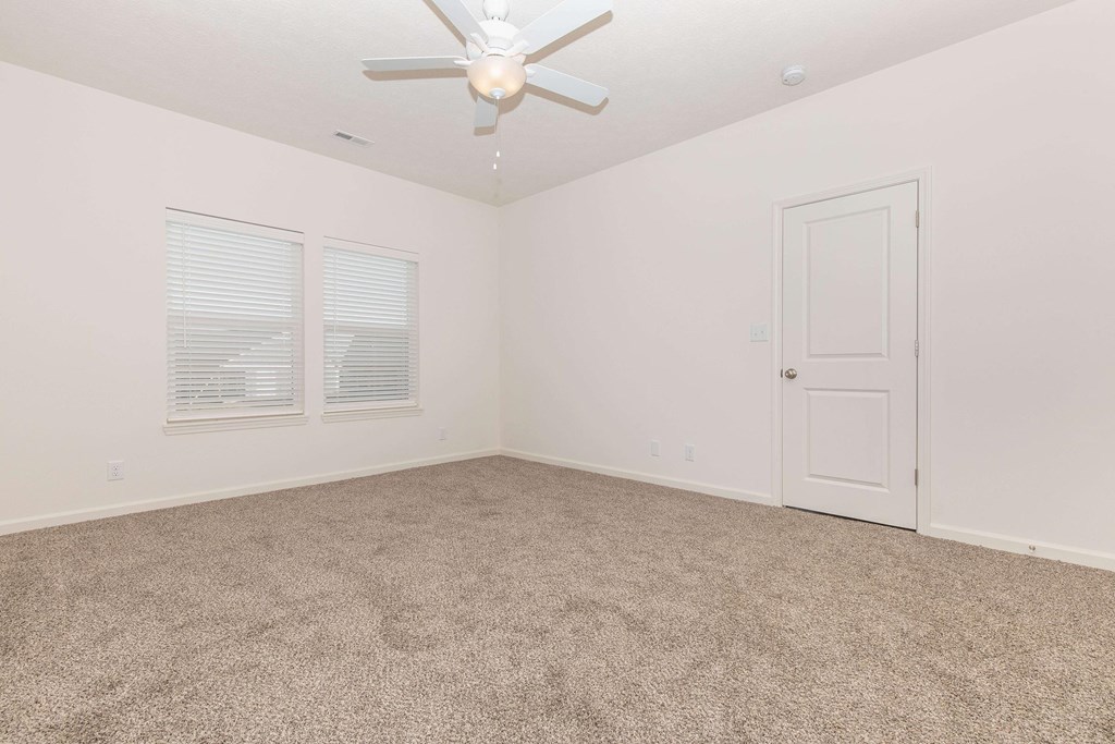 A room with a ceiling fan and carpeted floor.