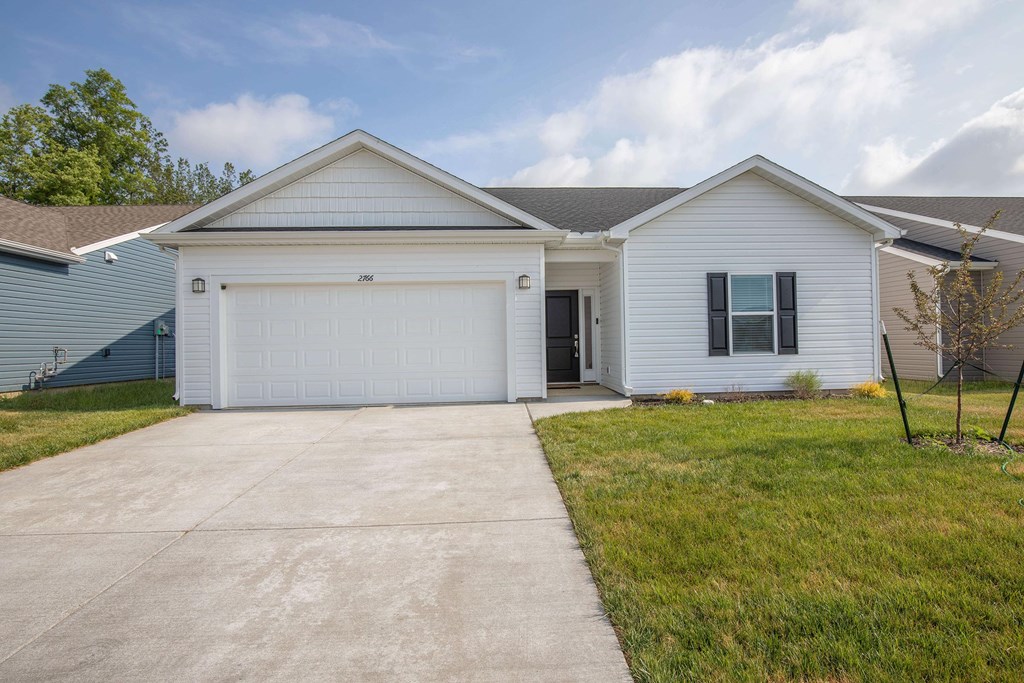 A white house with a garage door and a driveway.