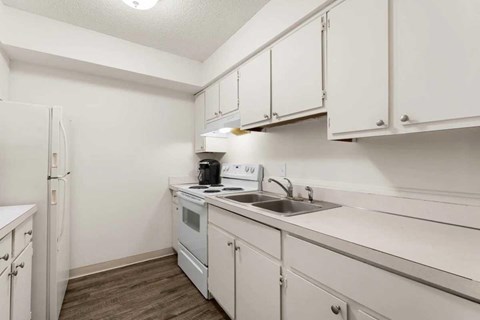 A small kitchen with white cabinets and a white fridge.