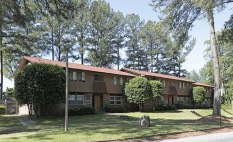 the front of a house with a lawn and trees